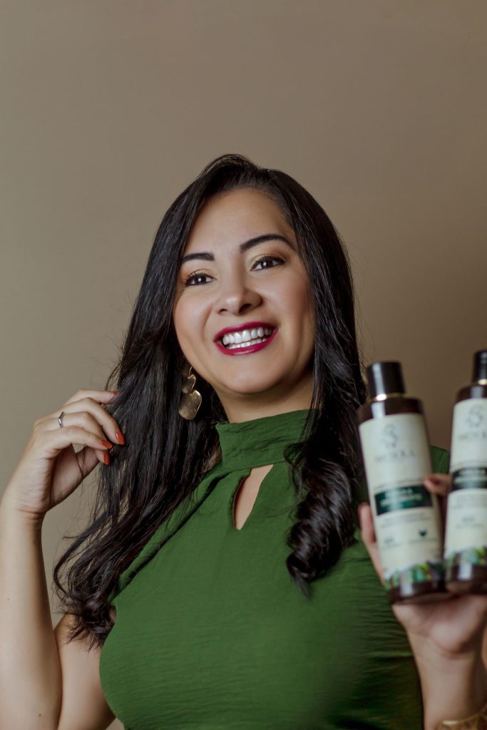 Woman smiling and holding hair-care product bottles