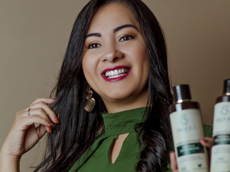Woman smiling and holding hair-care product bottles