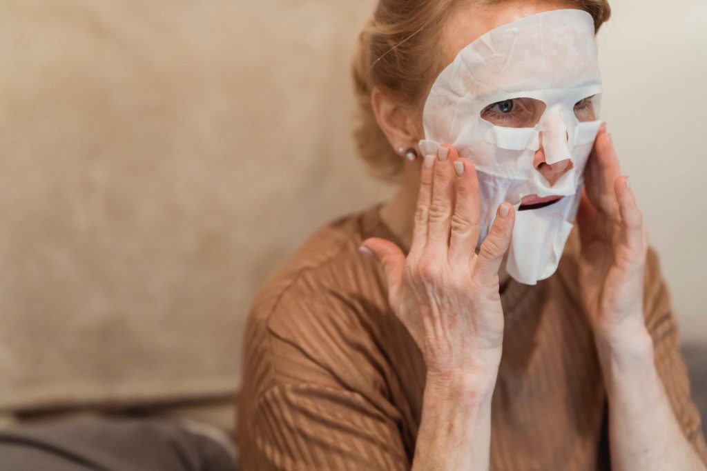 Senior woman applying a hydrating facial sheet mask