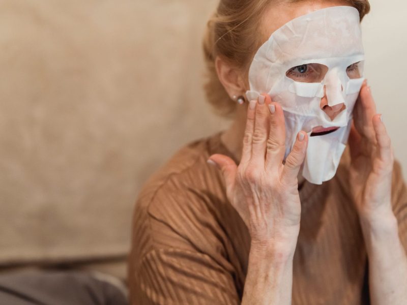 Senior woman applying a hydrating facial sheet mask
